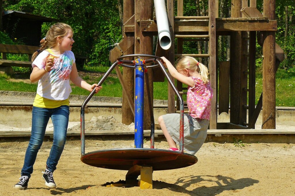 Due bambine giocano sulla giostra girevole nel parco giochi di Catania
