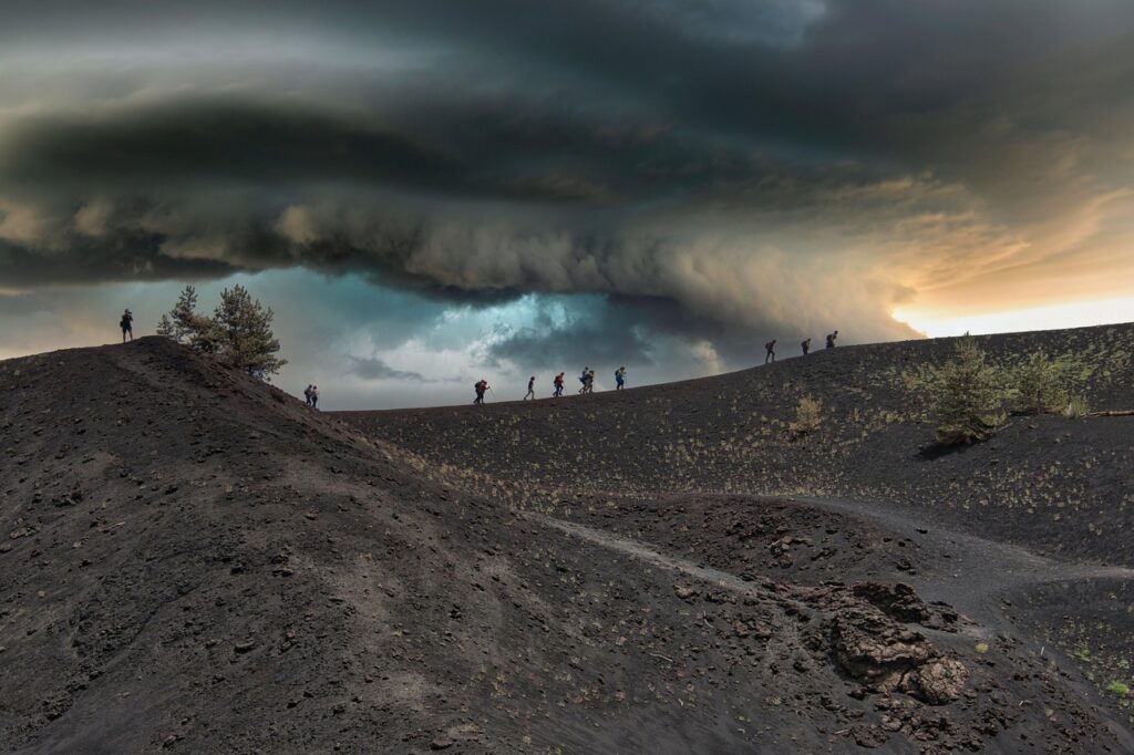 Silhouettes de randonneurs sur cendres volcaniques sous orage sur l'Etna