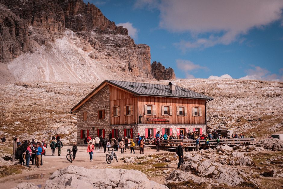 Refuge en pierre animé au pied de falaises rocheuses et randonneurs