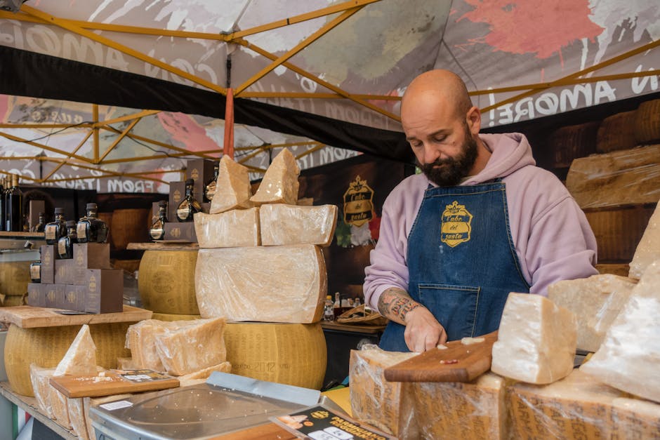 Venditore affetta grandi forme di formaggio allo stand della fiera piemontese
