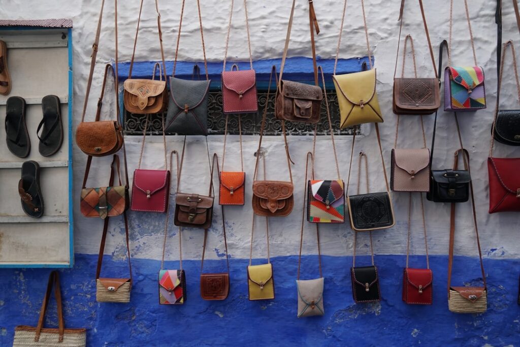 Artisan leather bags hanging on a blue wall at Piedmont market.