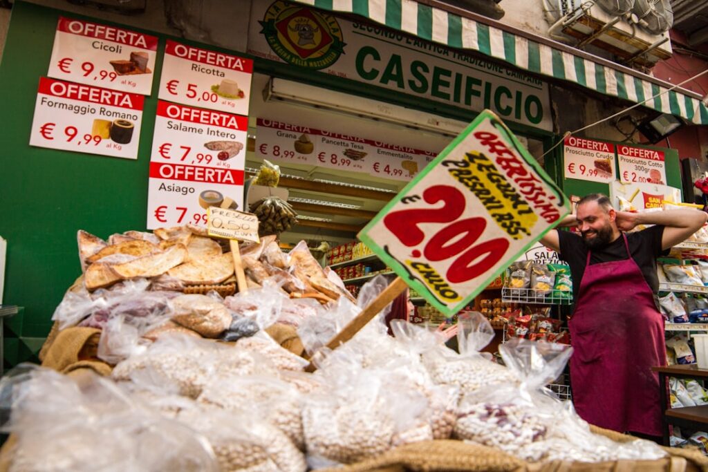 Cheese and pulses piled at a caseificio stall in Piedmont market, vendor smiling