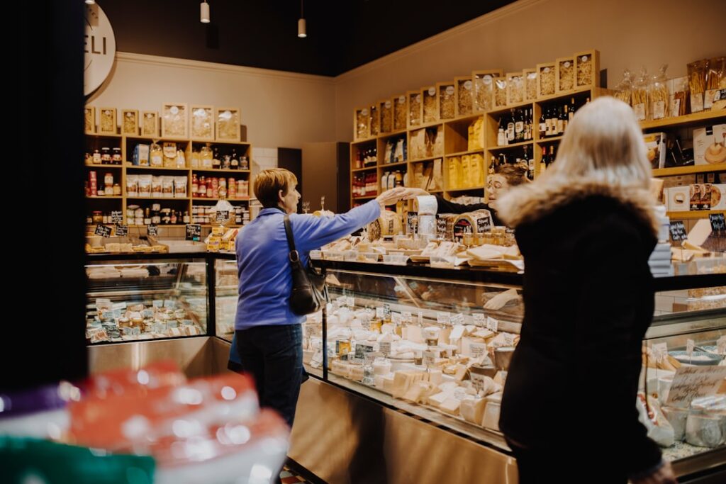 Customer exchanging payment at a Piedmont deli counter filled with cheeses