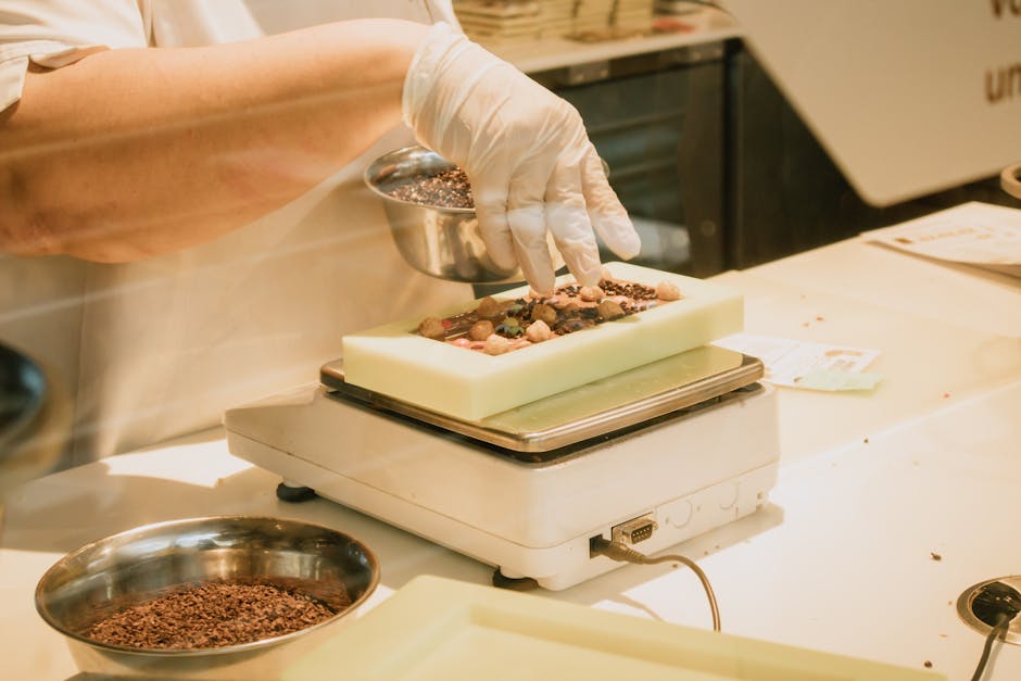 Artisan chocolatier in Piedmont adding nuts to chocolate mold.