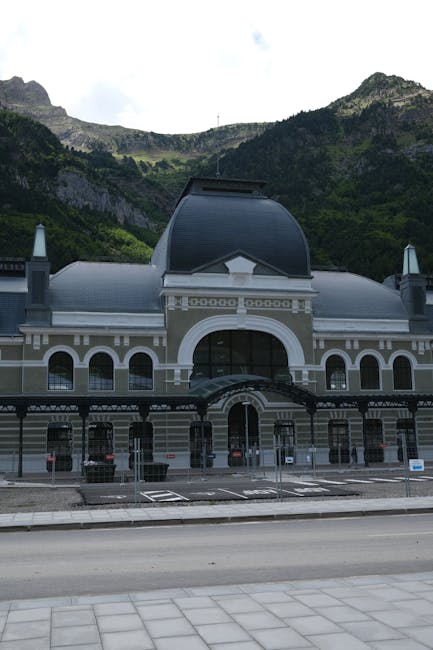 Historisches Bahnhofsgebäude vor bewaldeten Bergen, ruhige Straßenansicht
