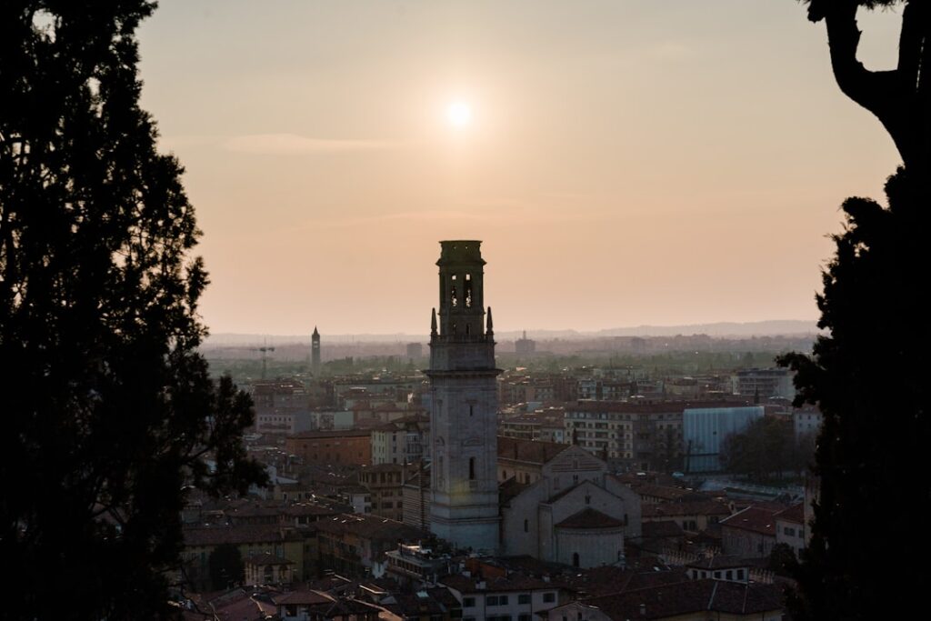 Zonsondergang boven stad met hoge klokkentoren, uitzicht over Piémont