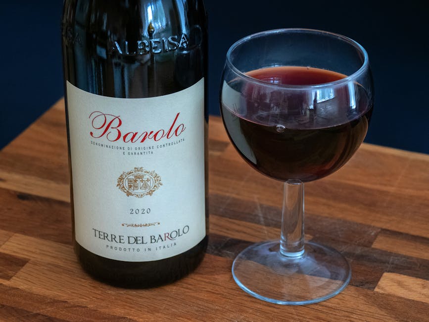 Fles Barolo wijn uit Piémont naast glas op houten tafel