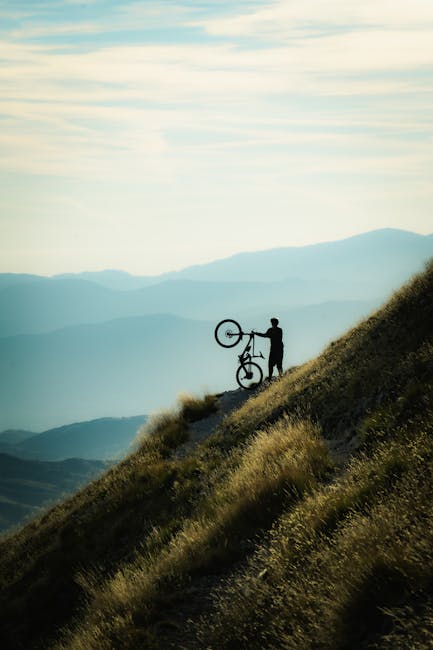 Silhouette eines Radfahrers trägt Mountainbike am steilen Hang im Piemont