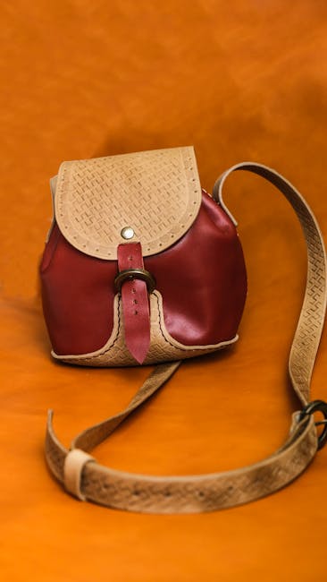 Kleiner roter Lederrucksack mit geprägten Details vor orangefarbenem Hintergrund, Piemont
