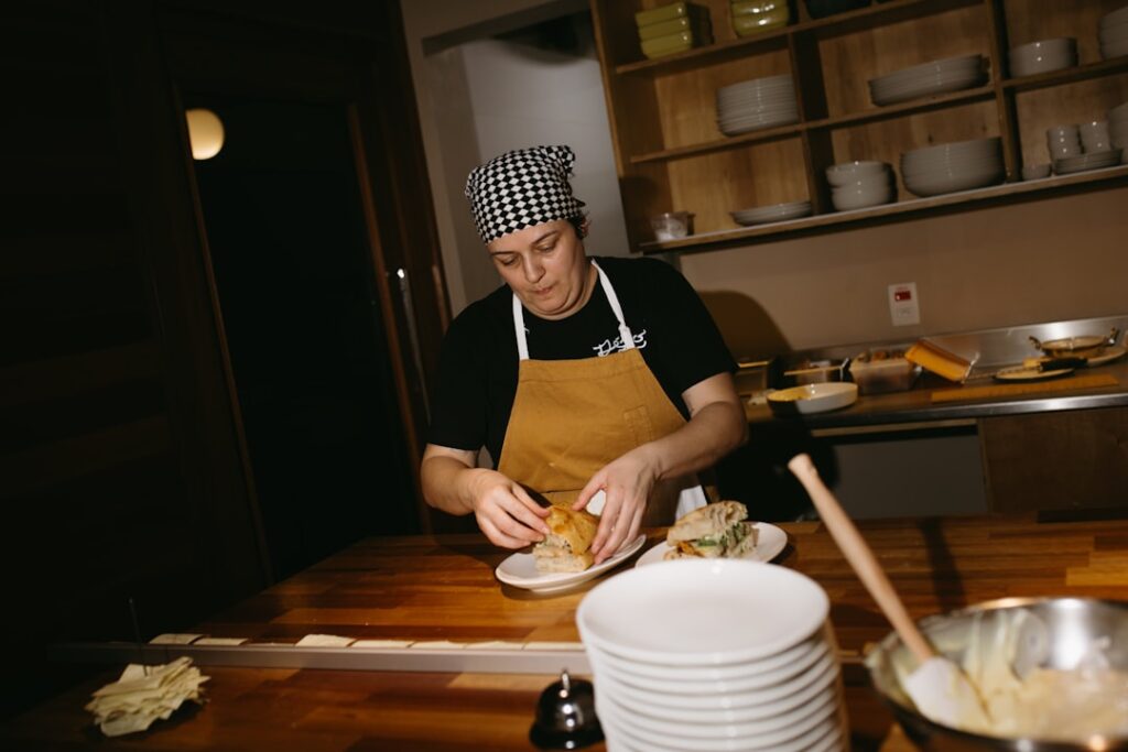 Cuoca con bandana prepara panino su banco di legno in cucina
