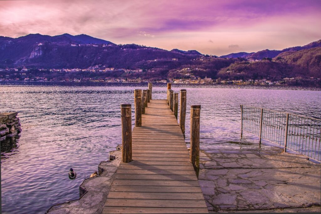 Pontile di legno che si protende sul lago piemontese al tramonto