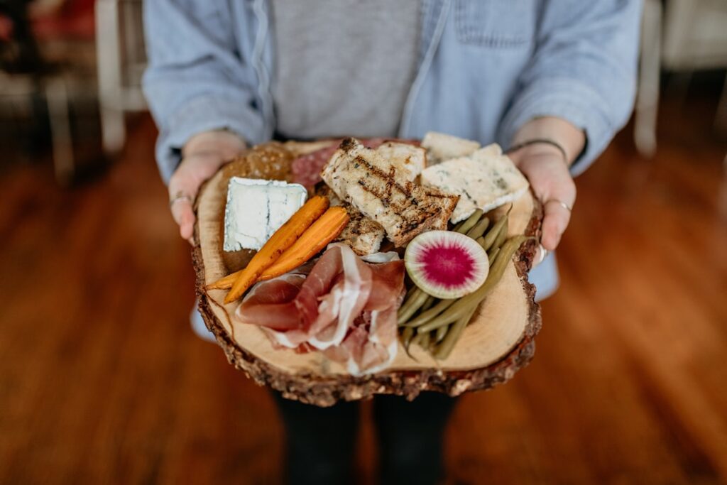 Person holding rustic Piedmont charcuterie and cheese board.