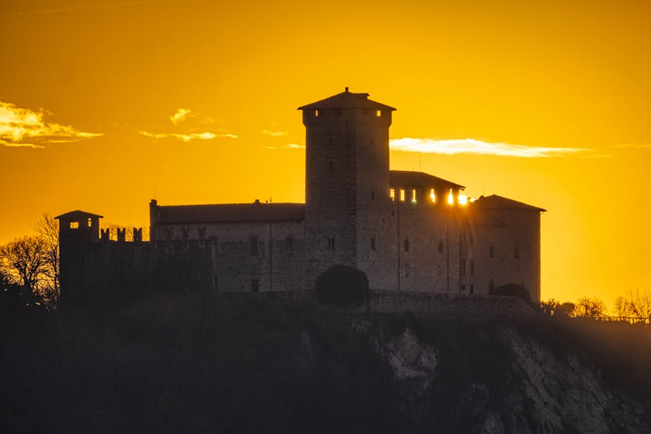Sonnenuntergang hinter Burgturm, warmes goldenes Licht im Piemont.