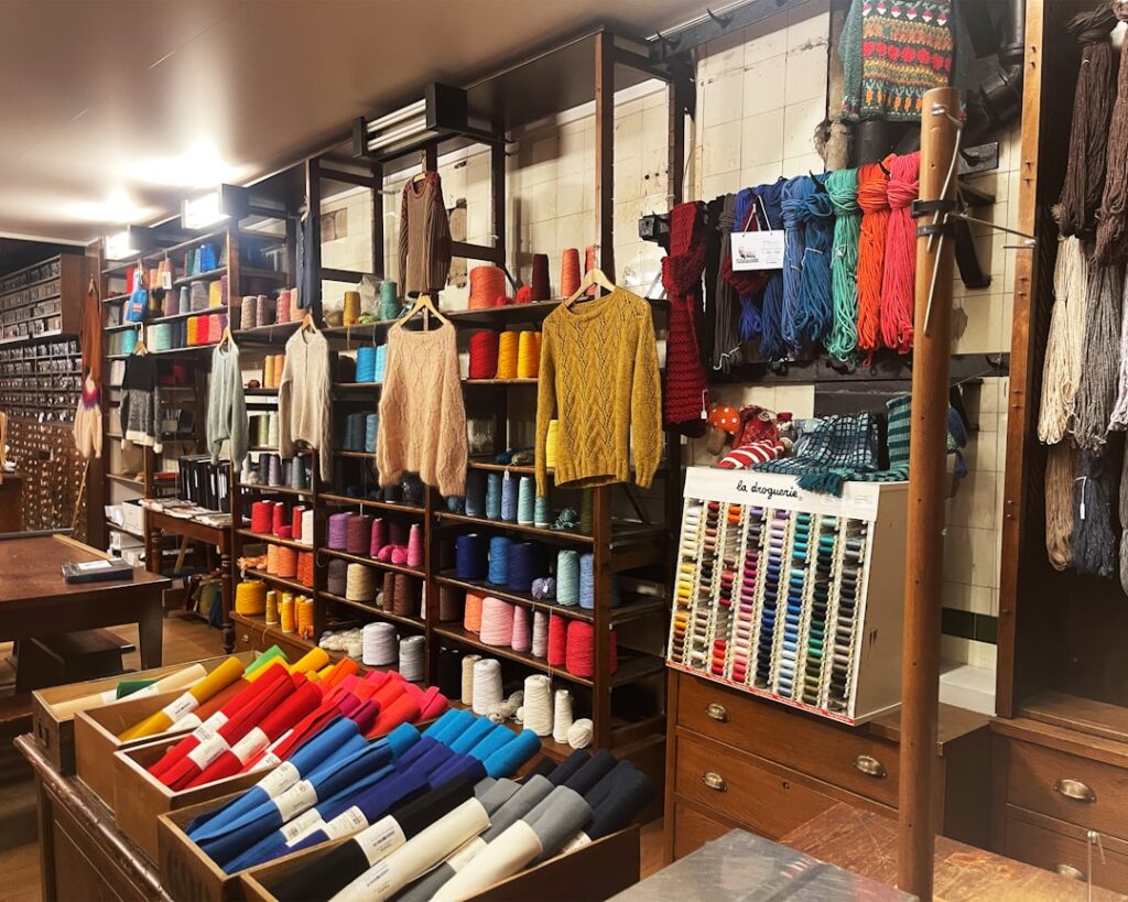 Étagères remplies de pelotes colorées et pulls dans une boutique piémontaise