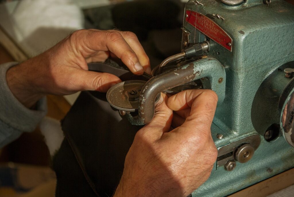Mani di artigiano piemontese che lavorano una cucitrice per pelle