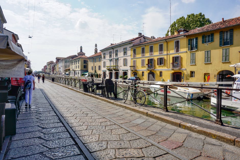 Cobblestone canal promenade lined with yellow riverside buildings and bicycles