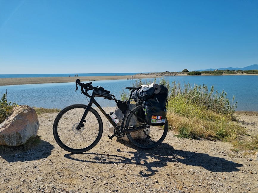 Beladenes Fahrrad an sandigem Ufer mit ruhigem Wasser beim Piemont-See