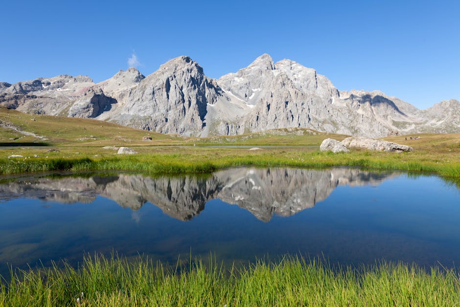 Rugged peaks mirrored perfectly in an alpine tarn in Piedmont