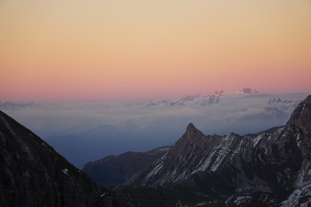 Sunrise pastel sky over jagged Piedmont Alps ridgeline and low clouds