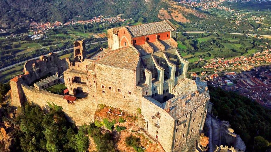 Ancient hilltop monastery overlooking tiled roofs and valley town in Piedmont