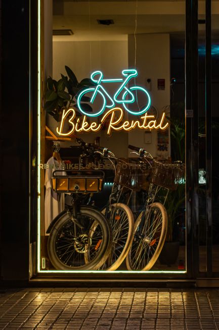 Enseigne néon 'Bike Rental' et vélos alignés derrière la vitrine à Piémont