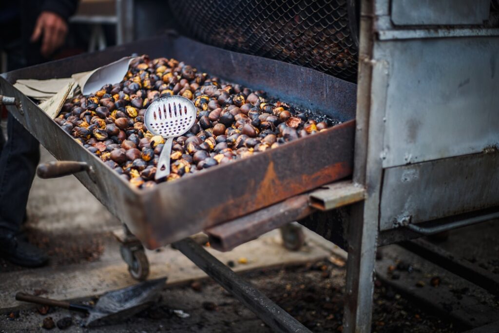 Carrello con castagne arrostite e mestolo accanto al forno da strada in Piemonte