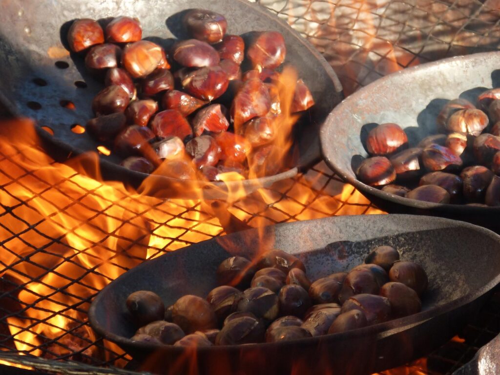 Padelle di castagne che arrostiscono su fuoco vivo alla festa piemontese