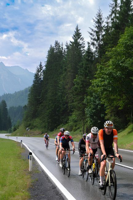 Groupe de cyclistes roule sous la pluie sur une route forestière piémontaise