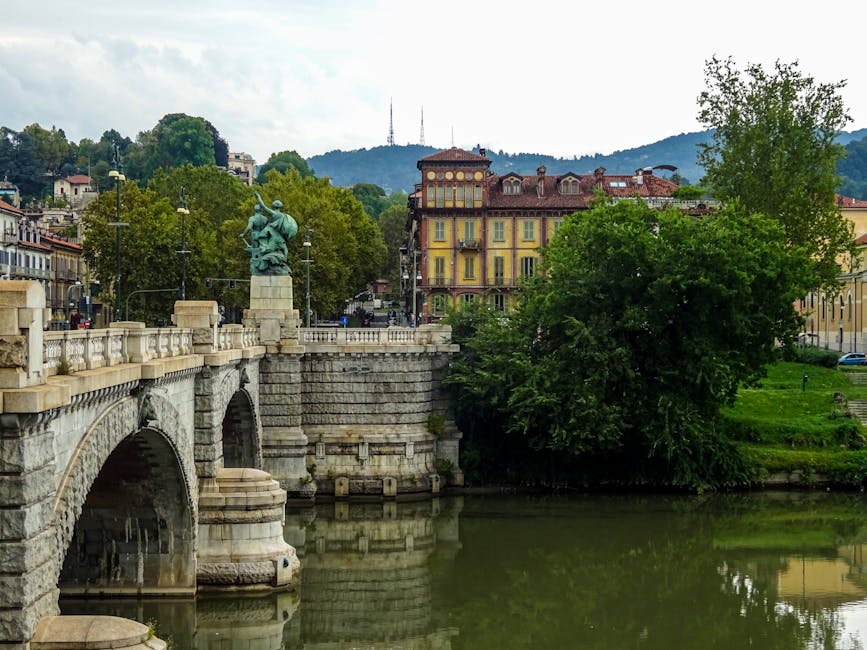 Steinbrücke über den Fluss mit Statue und Häusern in Turin, Piemont