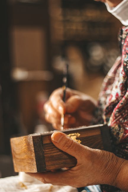 Mains d'artisan peignant un coffret en bois dans l'atelier