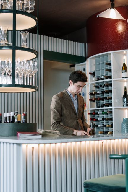 Sommeliersachtige man bij modern wijnbar met rekken vol flessen