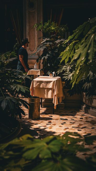 Intieme terrashoek met gedekte tafels tussen planten in Piémontse restaurant