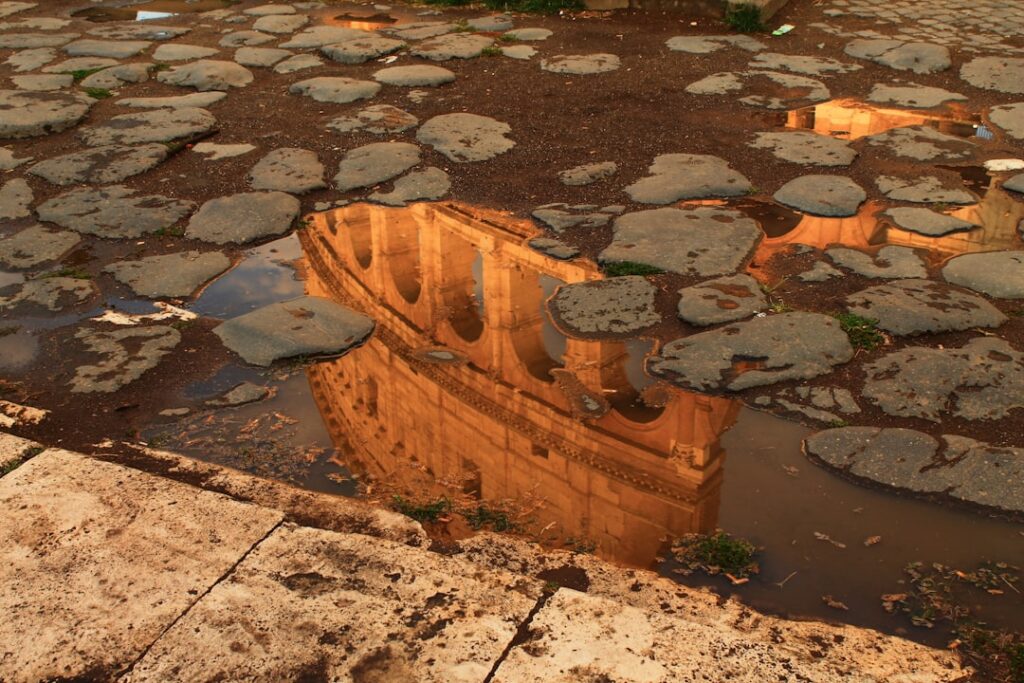 Reflectie van oud steengebouw in plas tussen Romeinse kasseien in Latium