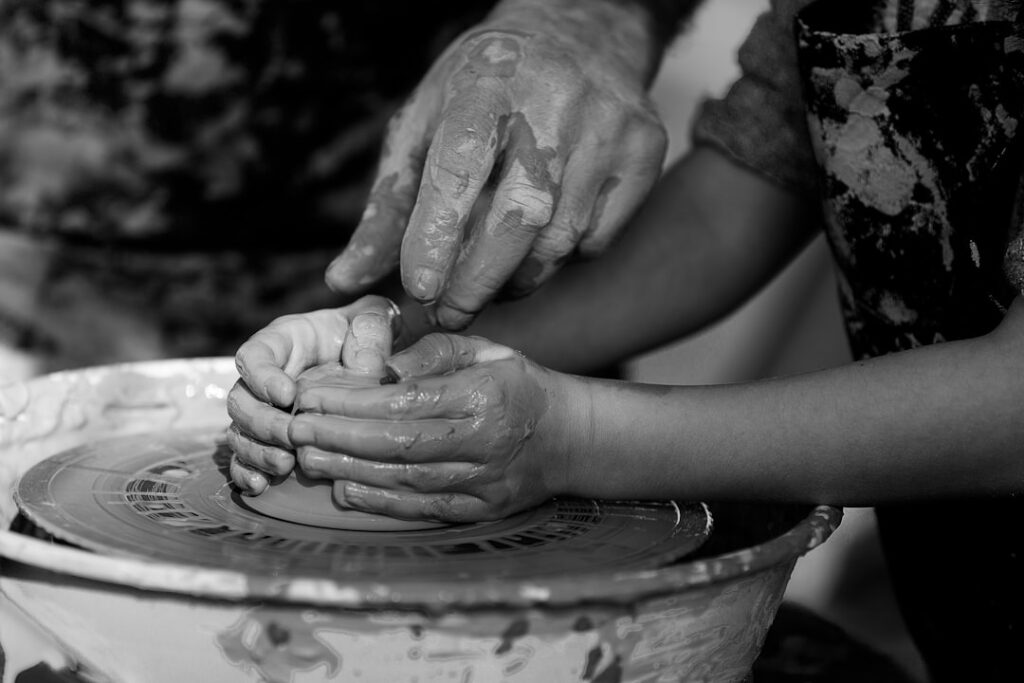 Instructor guiding child's hands at a pottery wheel in Civita Castellana