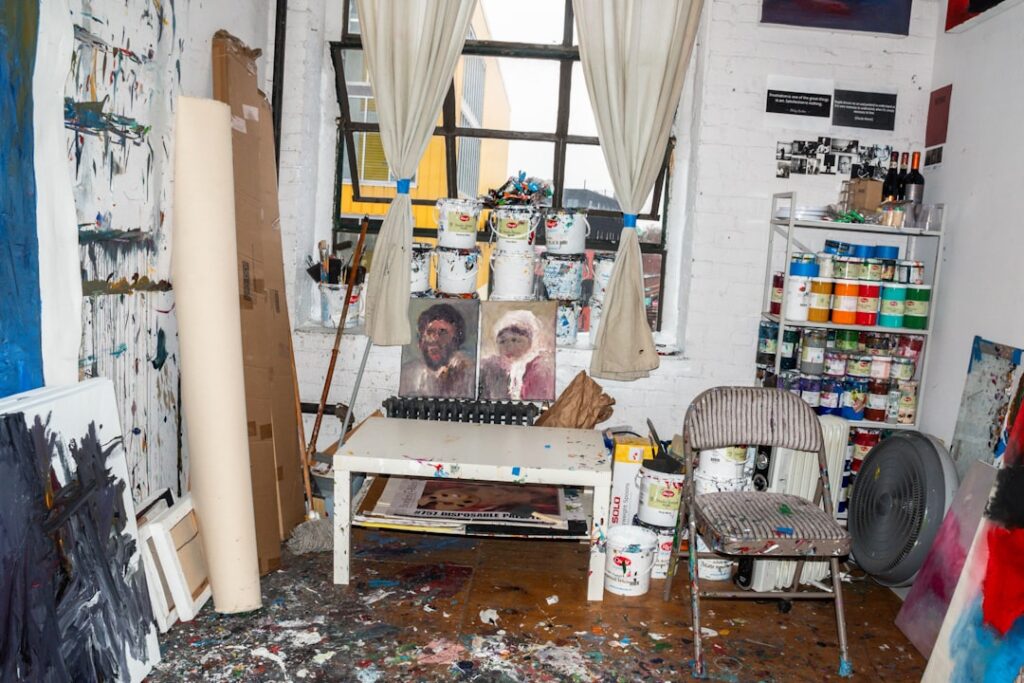 Chaotisch atelier in Latium met verfblikken, doeken en een raam