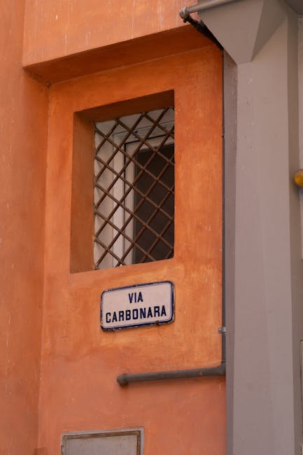 Schild 'Via Carbonara' an orangefarbener Fassade in den Gassen Roms