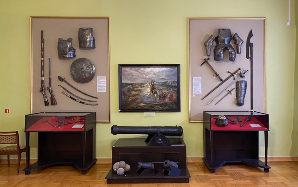 Salle d'exposition avec armures, armes et canon, musée du Latium