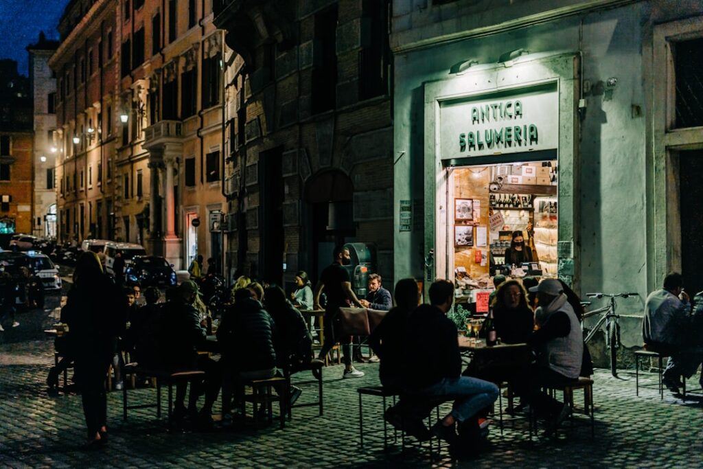 Abendliche Straßenszene mit Außenbestuhlung vor Antica Salumeria in Rom
