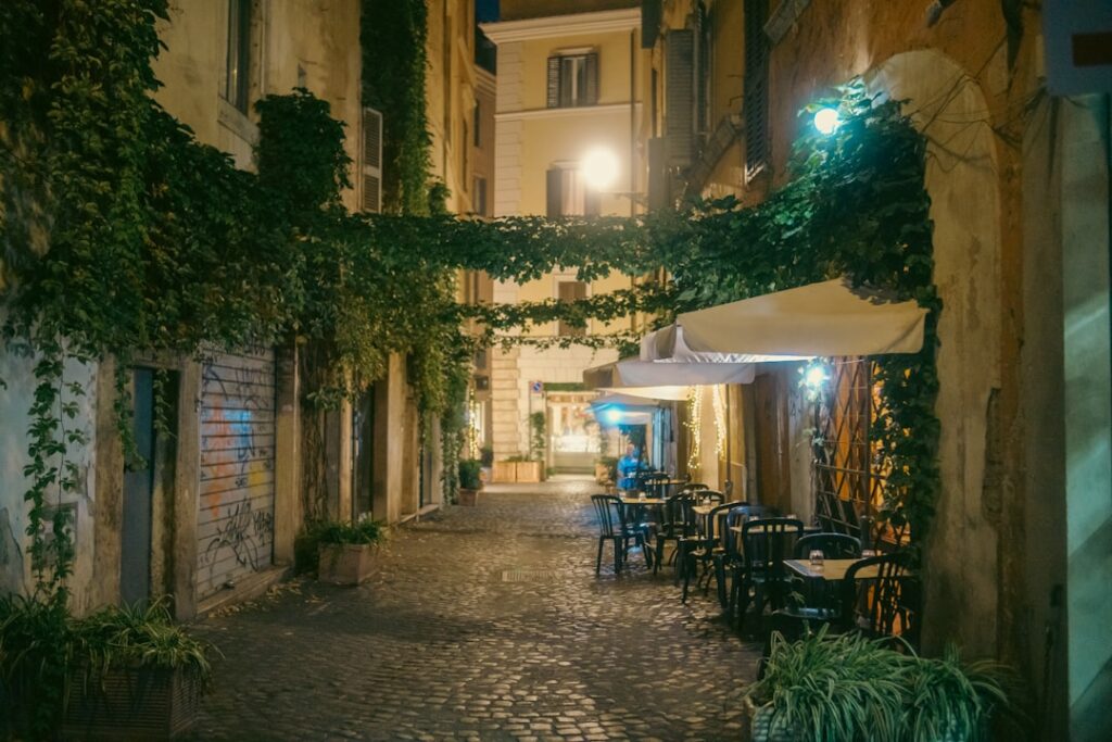 Gepflasterte Gasse in Trastevere, Latium, mit beleuchteten Außentischen