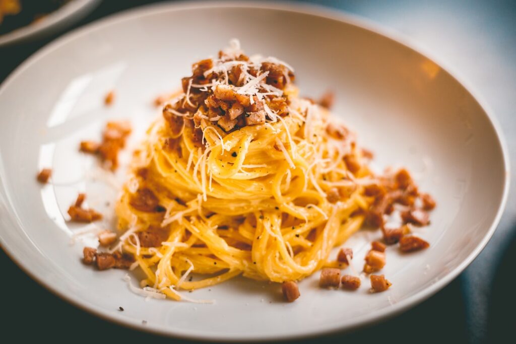Cremegelbe Carbonara mit Guanciale und Pecorino auf weißem Teller in Latium