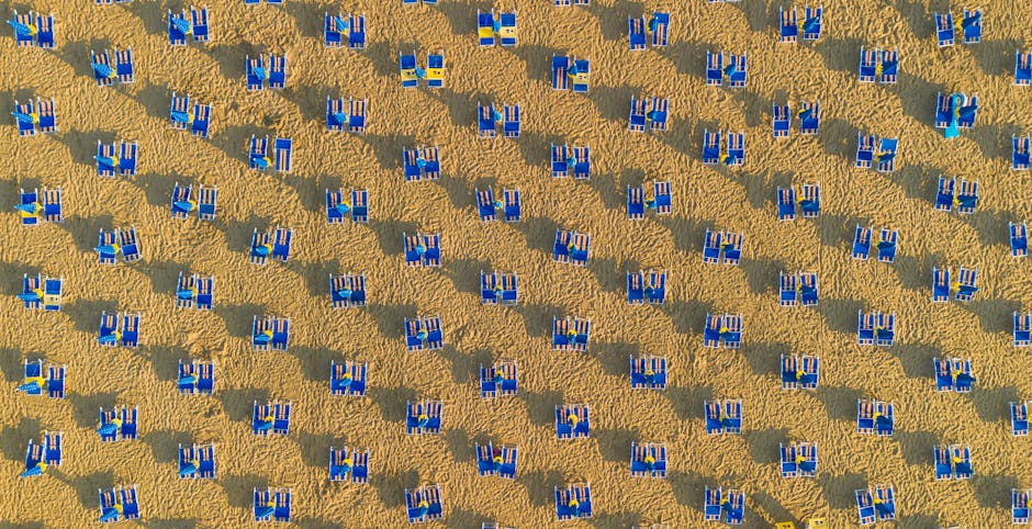 Drohnenaufnahme dichter blauer Liegestuhlreihen auf Sandstrand in Lido di Ostia, Latium