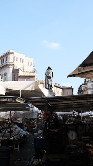 Outdoor market stalls with a central statue silhouette under blue sky in Rome, Latium