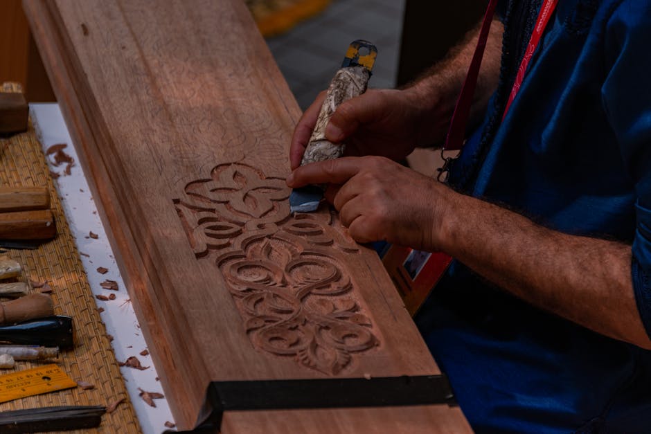 Mani che intagliano motivi floreali su pannello di legno