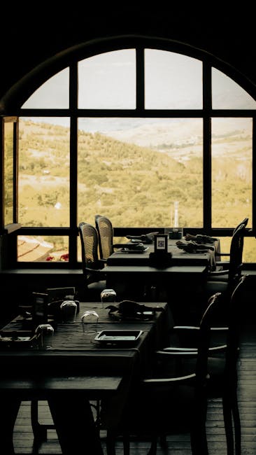 Tables silhouettées devant grande fenêtre offrant vue sur les collines du Latium.