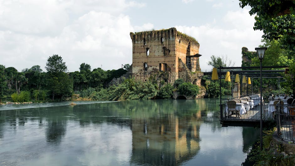 Oude toren langs rustige rivier met terras en tafels in Latium