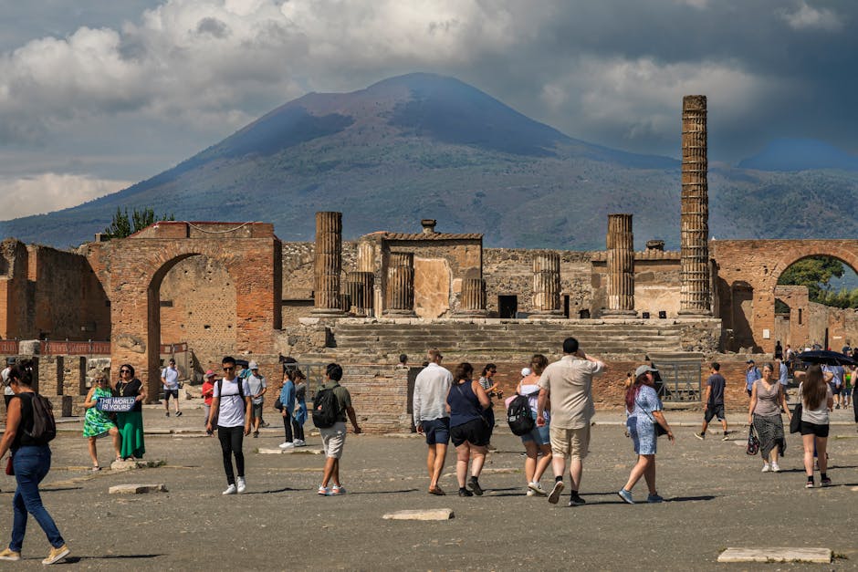 Touristen vor Tempelruinen in Pompeji, Vesuv deutlich am Horizont
