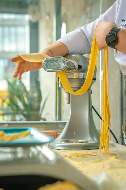 Kok voert pastavellen door machine, lange slierten drogen in Latium