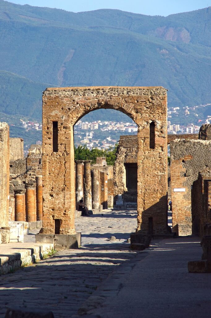 Antiker Torbogen und Säulen in Pompeji mit Bergen im Hintergrund