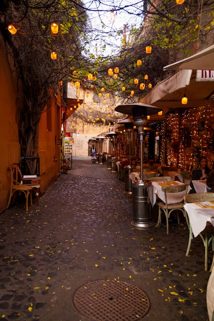 Cobblestone alley lined with trattoria tables and lanterns in Rome, Latium