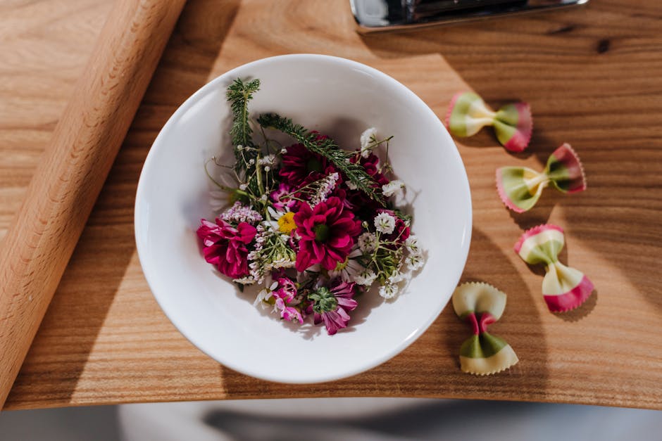 Witte kom met eetbare bloemen naast farfalle op Latium-werkbank